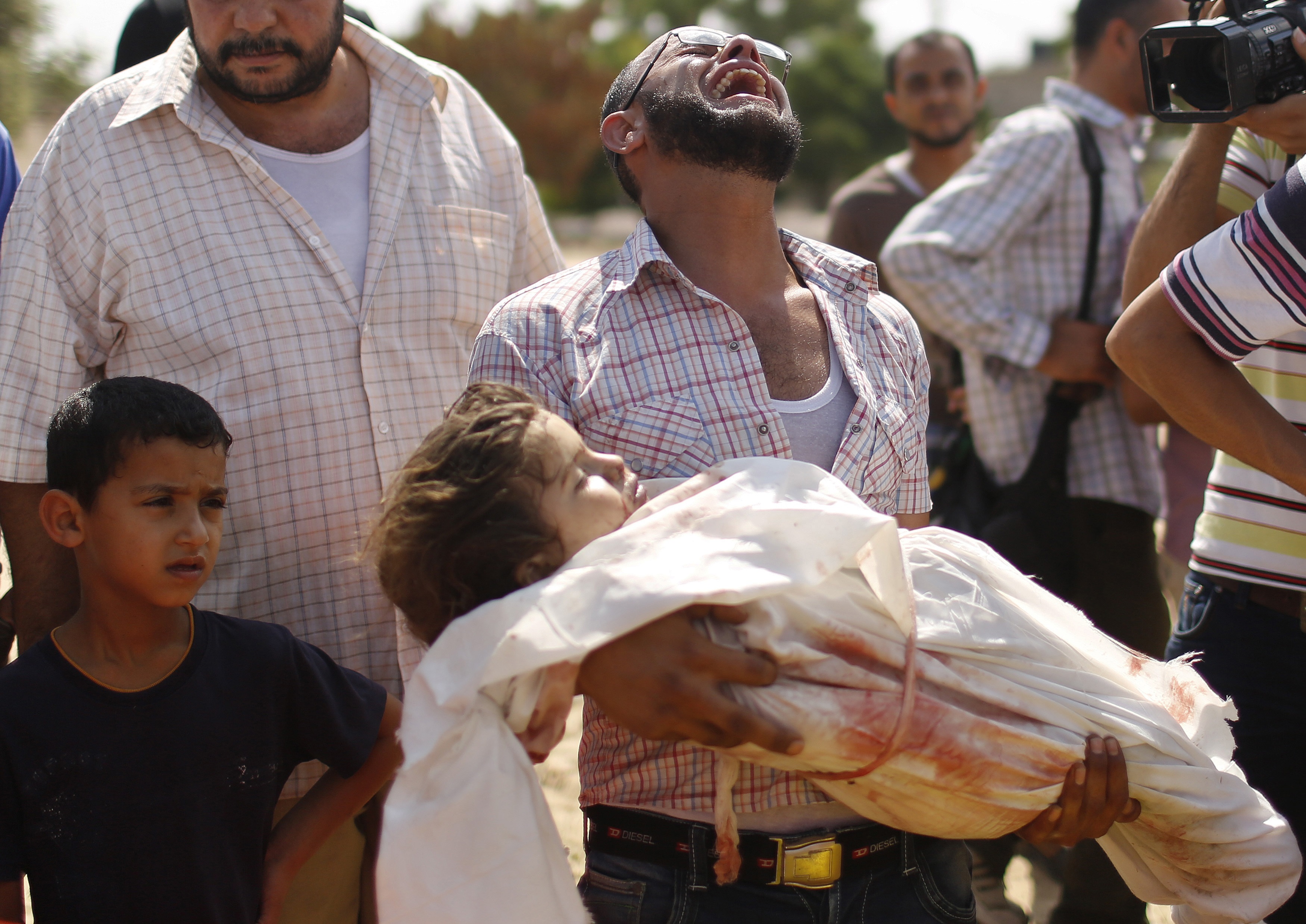 A relative cries as he carries the body of a three-year-old Palestinian girl, who medics said was killed by an Israeli tank shell, during their funeral in Beit Lahiya